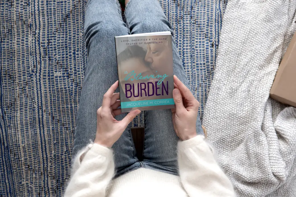 A woman reading The Blessing in the Burden
on a couch, the book held in her lap